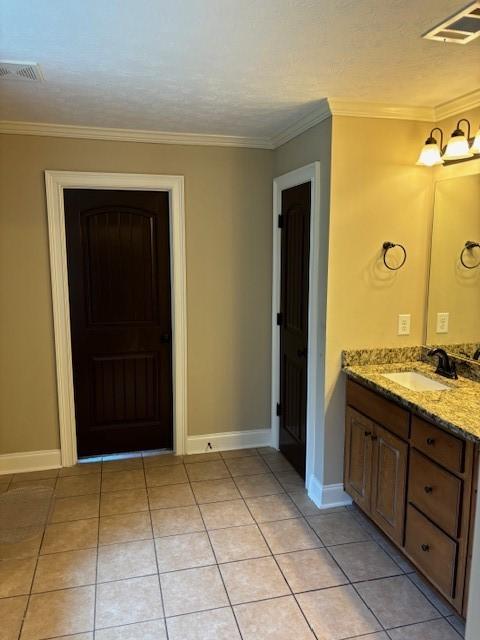 bathroom featuring ornamental molding, visible vents, baseboards, and tile patterned floors