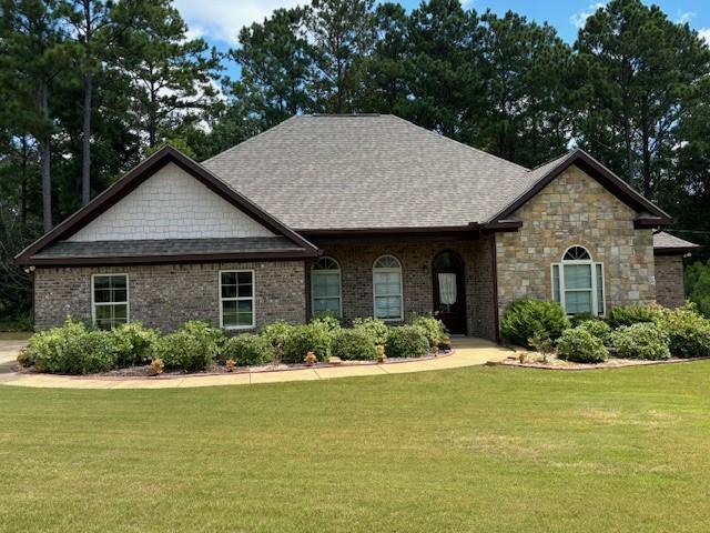 view of front of home featuring brick siding, a shingled roof, and a front yard