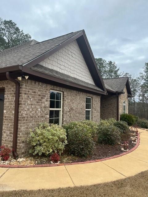 view of home's exterior featuring roof with shingles and brick siding