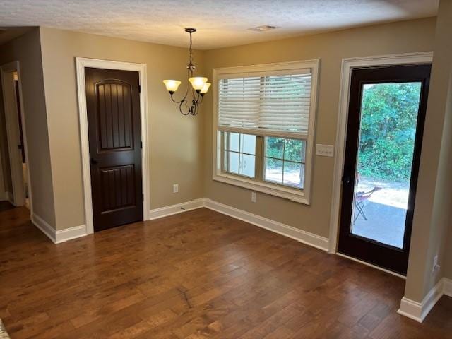 entryway featuring a chandelier, dark wood finished floors, and baseboards