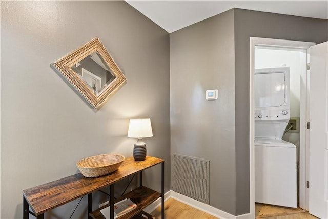 corridor with visible vents, stacked washer and dryer, baseboards, and light wood-style floors
