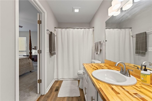 ensuite bathroom featuring visible vents, vanity, wood finished floors, toilet, and a shower with shower curtain