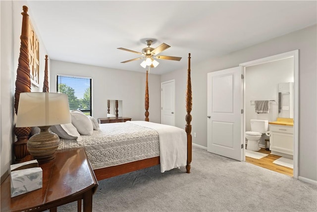 bedroom featuring connected bathroom, baseboards, light colored carpet, and ceiling fan