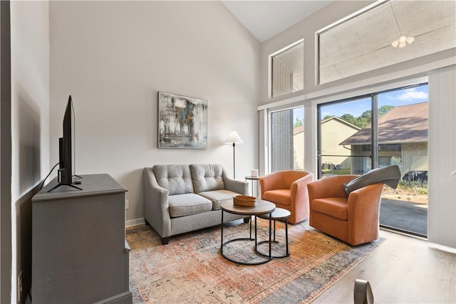 living room with baseboards, high vaulted ceiling, and wood finished floors