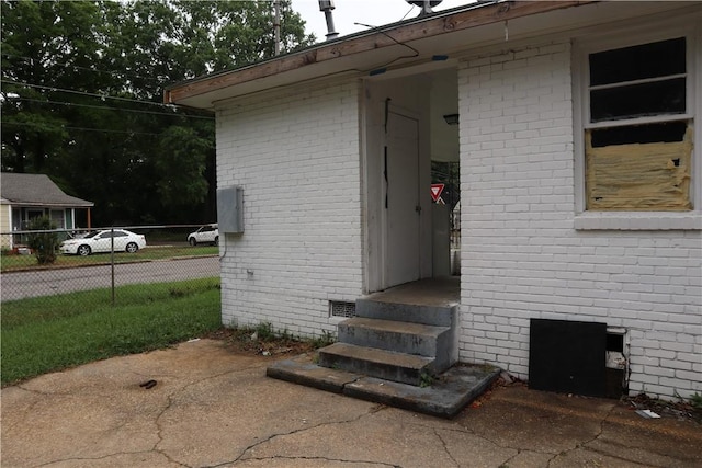 entrance to property with crawl space, fence, and brick siding