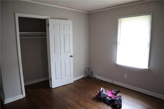 unfurnished bedroom featuring wood finished floors, ornamental molding, baseboards, and a closet