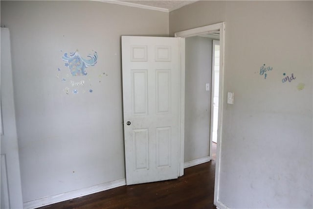 unfurnished bedroom featuring wood finished floors, ornamental molding, and baseboards
