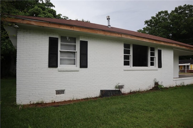 view of home's exterior with a lawn, crawl space, and brick siding