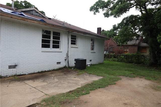 view of side of home featuring crawl space, brick siding, central air condition unit, and a yard