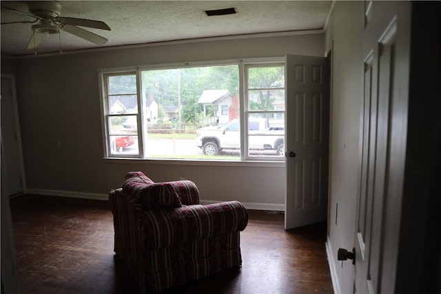 living area featuring healthy amount of natural light, baseboards, dark wood finished floors, a ceiling fan, and ornamental molding