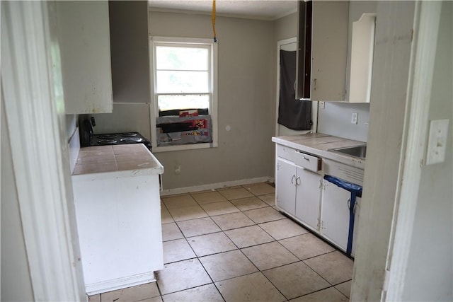 kitchen featuring light tile patterned floors, white cabinetry, crown molding, and baseboards