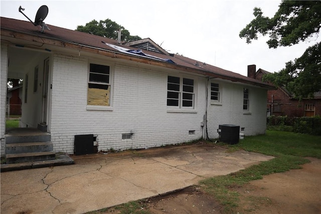 rear view of house with crawl space, brick siding, central AC unit, and a patio