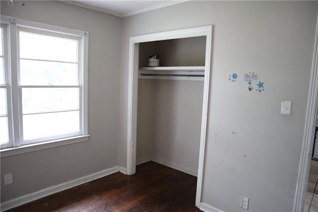 unfurnished bedroom with a closet, dark wood-style flooring, multiple windows, and baseboards