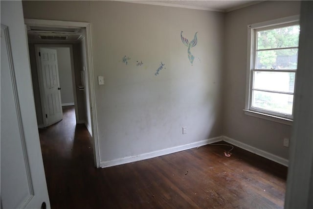 unfurnished room with dark wood finished floors, plenty of natural light, baseboards, and crown molding