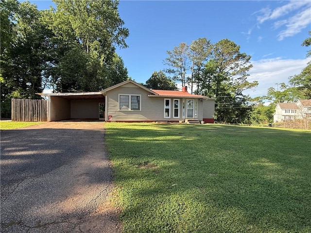 ranch-style home featuring driveway, an attached carport, a chimney, and metal roof