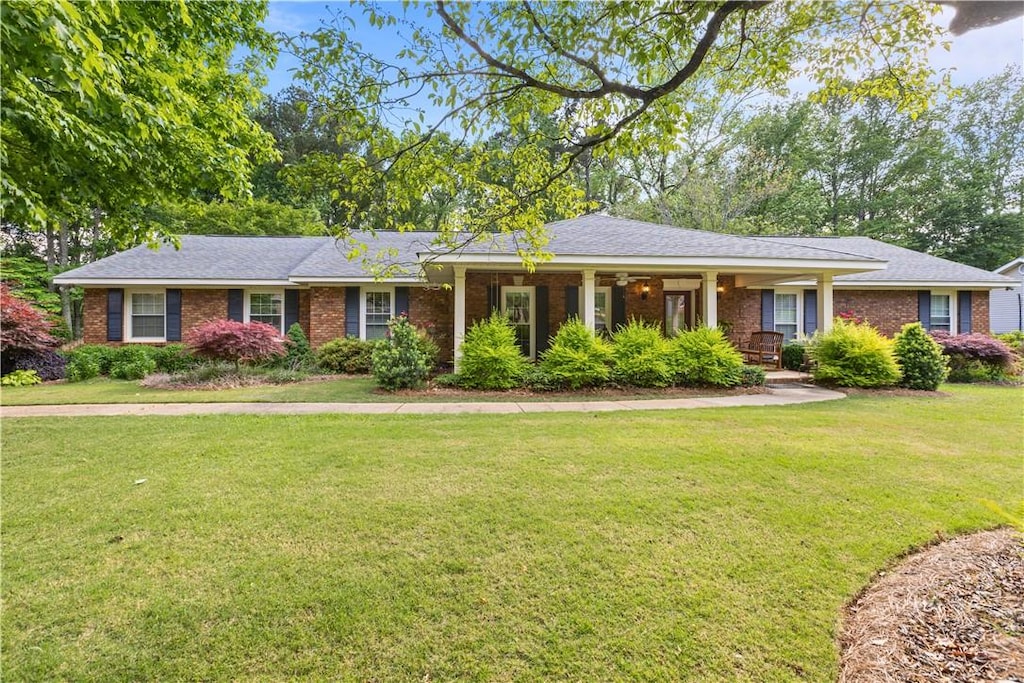 ranch-style home featuring a front yard, covered porch, and brick siding