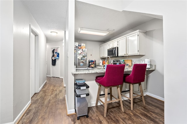 1041 Stonegate Dr Unit C, Auburn, AL 36830 - kitchen featuring appliances with stainless steel finishes, wood finished floors, baseboards, white cabinetry, and a textured ceiling