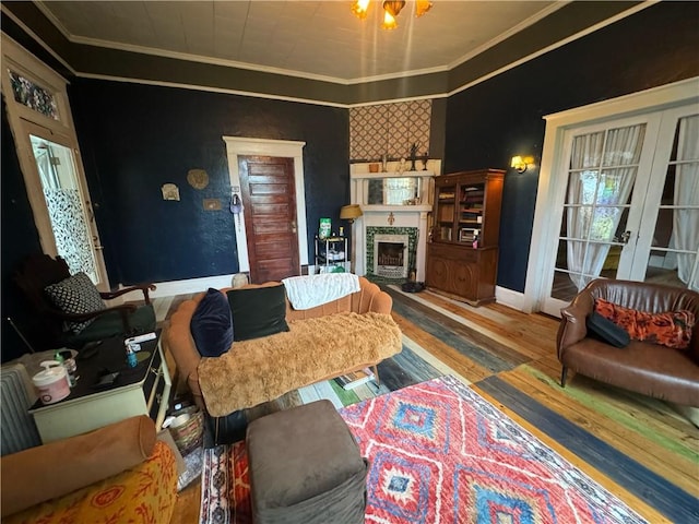 living room with a tiled fireplace, ornamental molding, hardwood / wood-style flooring, and french doors