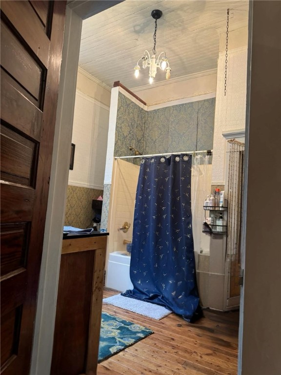 bathroom with shower / tub combo, hardwood / wood-style floors, ornamental molding, and a chandelier