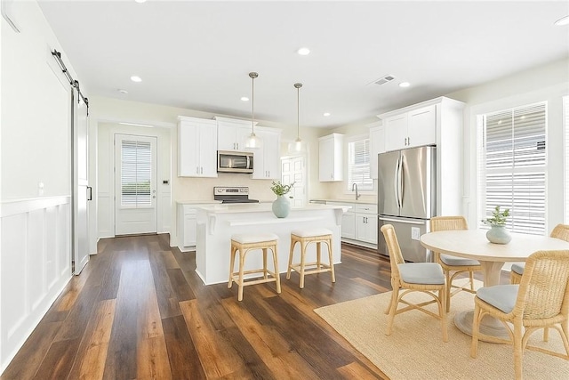 854 Village Dr, Opelika, AL 36801 - kitchen with appliances with stainless steel finishes, a kitchen island, light countertops, a barn door, and white cabinets
