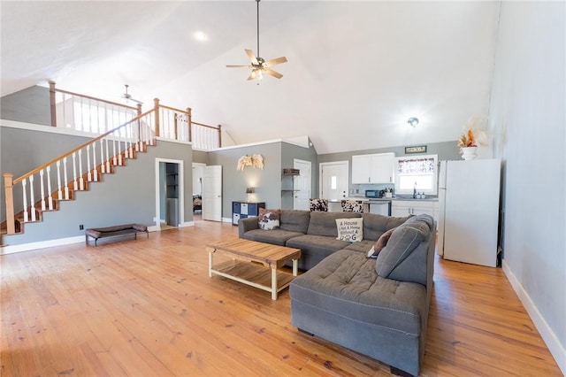 living room featuring ceiling fan, sink, and light wood-type flooring