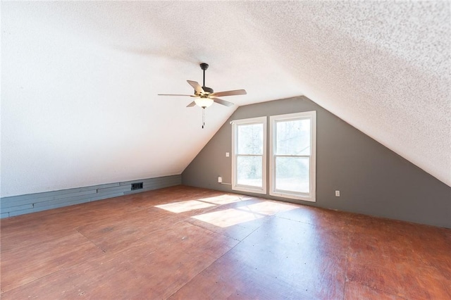 bonus room with hardwood / wood-style flooring, lofted ceiling, and a textured ceiling