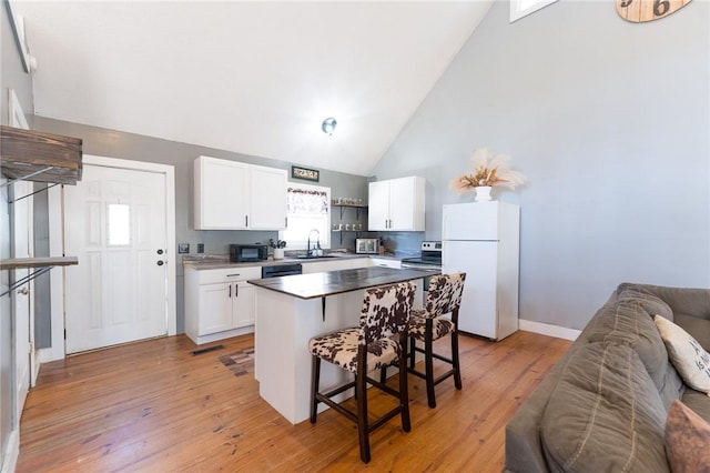 kitchen with a kitchen island, a breakfast bar area, white cabinets, black appliances, and light wood-type flooring