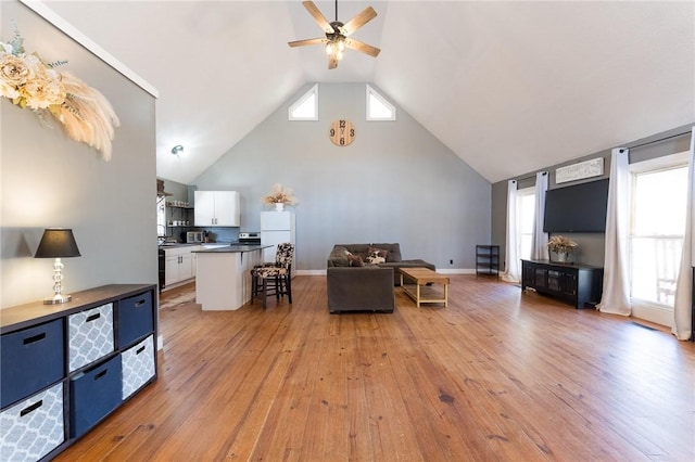 living room featuring light hardwood / wood-style flooring, high vaulted ceiling, and ceiling fan