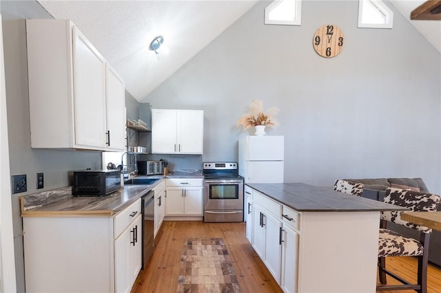 kitchen with sink, a breakfast bar, stainless steel appliances, light hardwood / wood-style floors, and white cabinets