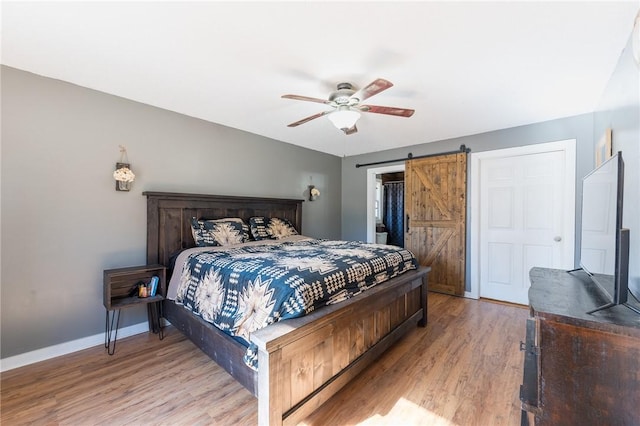 bedroom with a spacious closet, a closet, hardwood / wood-style flooring, ceiling fan, and a barn door