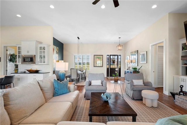 living room with ceiling fan with notable chandelier and light wood-type flooring