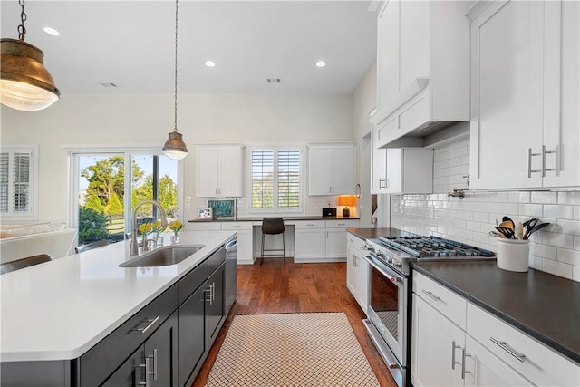 kitchen featuring decorative light fixtures, an island with sink, stainless steel appliances, and sink