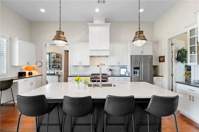 kitchen with backsplash, high end refrigerator, sink, and pendant lighting