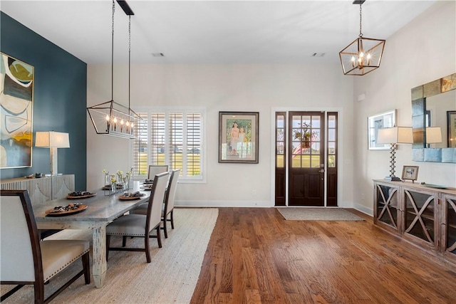 dining area with baseboards, wood finished floors, a notable chandelier, and plenty of natural light