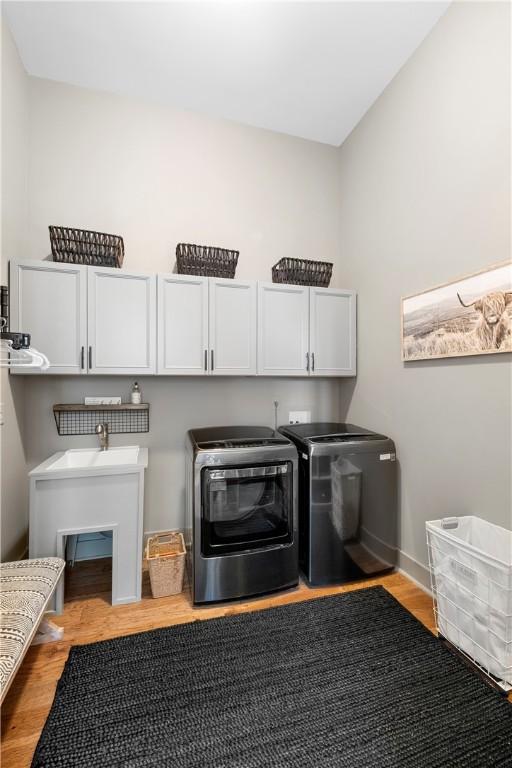 laundry area featuring cabinets, independent washer and dryer, and light wood-type flooring