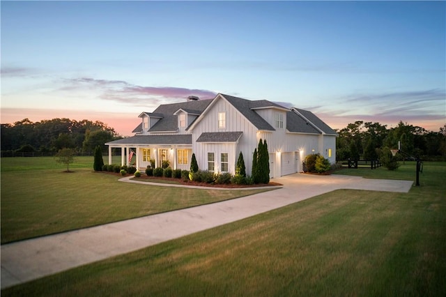 modern farmhouse style home featuring a garage, driveway, board and batten siding, and a lawn