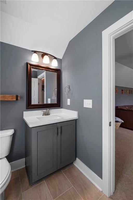 bathroom with vanity, lofted ceiling, and toilet