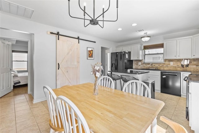 dining room featuring light tile patterned floors, a barn door, and visible vents