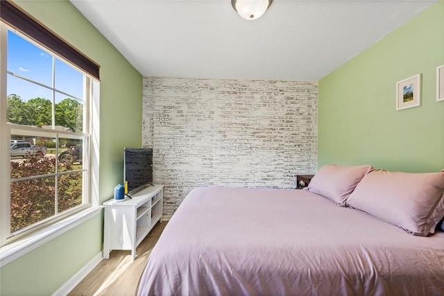 bedroom featuring baseboards, wood finished floors, and an accent wall