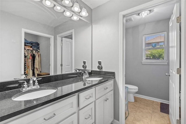 full bath featuring tile patterned floors, toilet, double vanity, and a sink