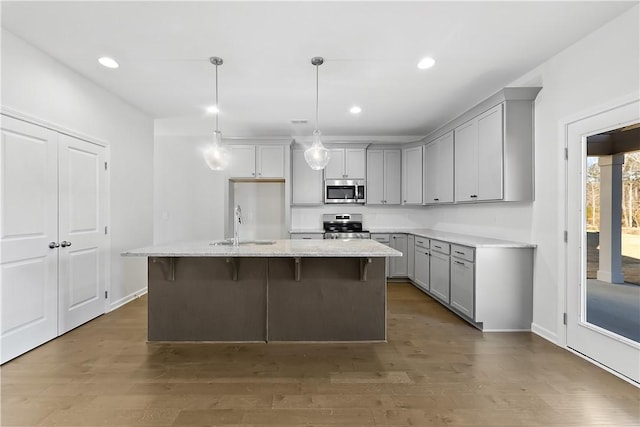 kitchen featuring sink, decorative light fixtures, dark hardwood / wood-style flooring, an island with sink, and stainless steel appliances