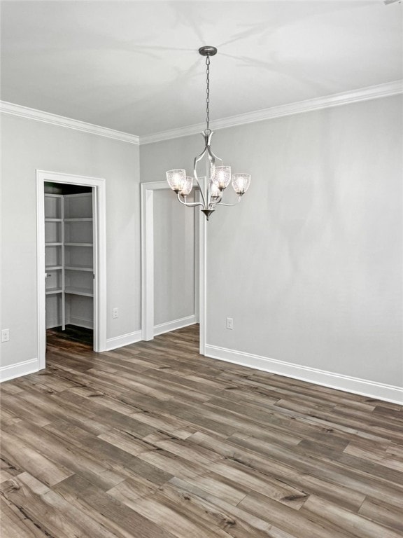 unfurnished dining area with crown molding, dark wood-type flooring, and a chandelier