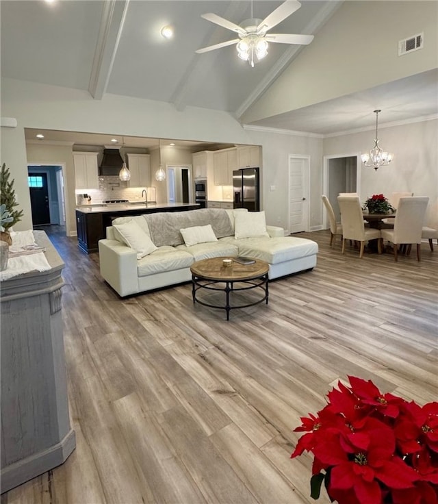 living room with light wood-type flooring, beam ceiling, ceiling fan with notable chandelier, and high vaulted ceiling