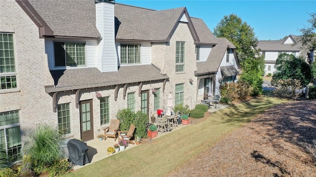 rear view of house with a lawn and a patio