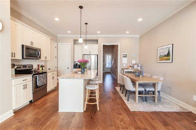 kitchen featuring light stone countertops, white cabinetry, stainless steel appliances, and a kitchen island with sink