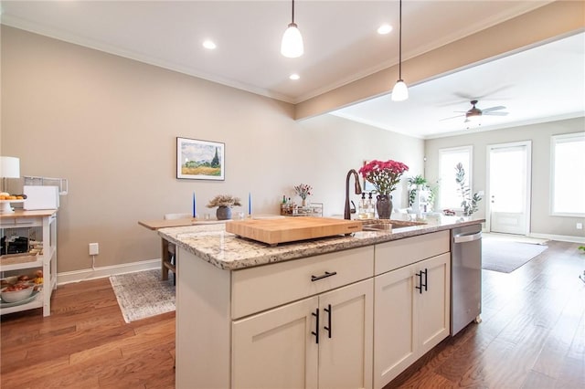 kitchen featuring dishwasher, light stone counters, decorative light fixtures, a kitchen island with sink, and ornamental molding