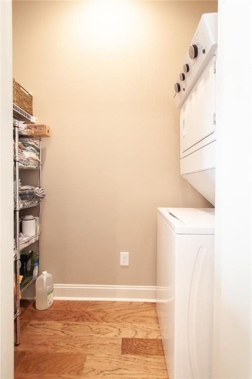 washroom featuring stacked washer and dryer and light hardwood / wood-style flooring