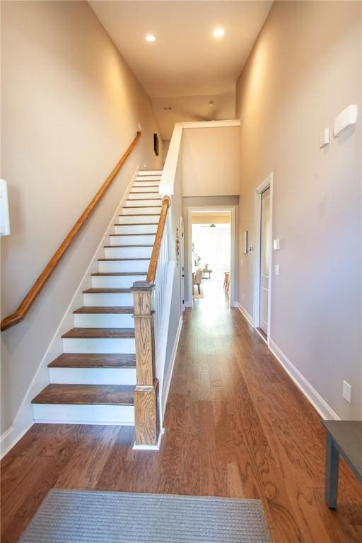 stairway with wood-type flooring and a high ceiling