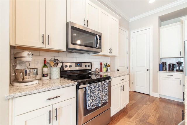 kitchen with decorative backsplash, white cabinets, and stainless steel appliances