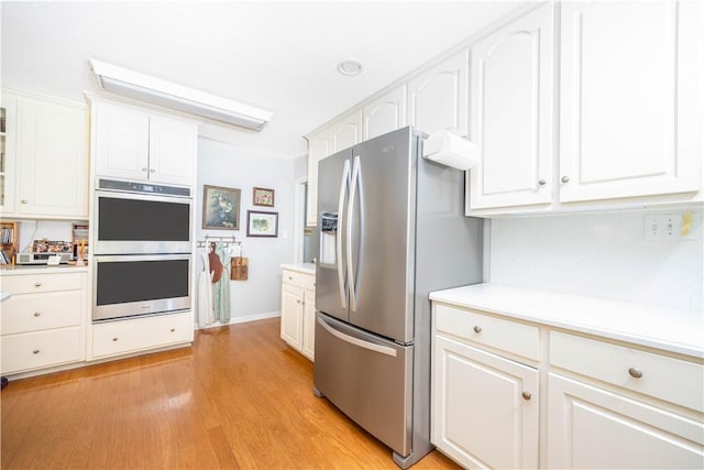 406 Saint Francis Rd, Eufaula, AL 36027 - kitchen with stainless steel appliances, light wood finished floors, light countertops, white cabinets, and decorative backsplash